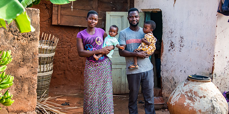 Moeder en vader uit Togo staan voor hun huis met hun dochters.