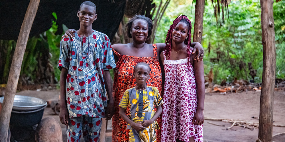 Esaïe uit Togo staat gearmd met zijn moeder, zus en broertje.